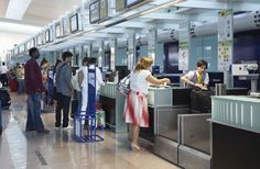 people waiting in line at an airport check - in counter