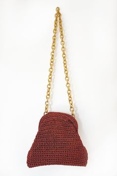 a red crocheted purse hanging from a gold chain on a white background,