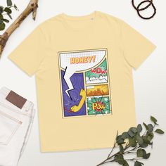 Comic Tee to enjoy 100% organic cotton. Soft and durable design. An eco-friendly made with 5.3 oz/yd², you'll love the cozy fit and feel.  * 100% organic ring-spun cotton * Fabric weight: 5.3 oz/yd² (180 g/m²) * Single jersey * Medium fit * Set-in sleeves * 1 × 1 rib at collar * Wide double-needle topstitch on the sleeves and bottom hems * Self-fabric neck tape (inside, back of the neck) * Blank product sourced from China or Bangladesh The sizes correspond to a smaller size in the US market, so Cotton Tops With Graphic Design, Cotton Graphic Design Top As Gift, Fun Cotton T-shirt As A Gift, Eco-friendly Cotton Top With Graphic Print, Eco-friendly Cotton Graphic T-shirt, Comic-con Graphic Cotton T-shirt, Honey Gifts, Organic Rings, Cozy Fits