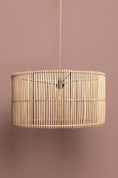 a rattan light fixture hanging from a ceiling in a room with a pink wall