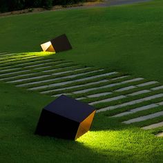 two black and yellow cubes sitting on top of grass next to steps in the middle of a field