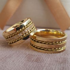 two gold wedding rings sitting on top of each other