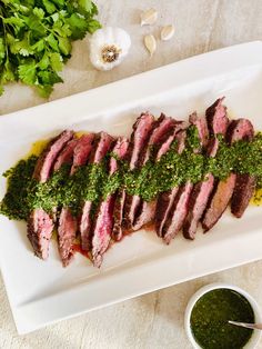 sliced steak with pesto and sauce on a white platter