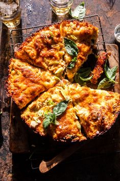 a pizza sitting on top of a wooden cutting board next to wine glasses and utensils