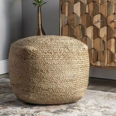 a large round jute basket sitting on top of a rug next to a vase