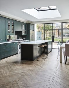 a kitchen with an island and skylight in the center, surrounded by wooden flooring