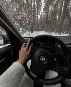 a person driving a car in the snow with their hands on the steering wheel and dashboard