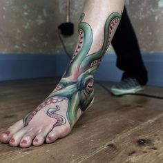 an octopus tattoo is on the foot of a man with his feet covered in tattoos