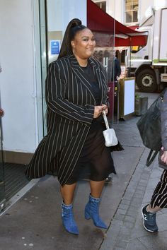 a woman in black and white striped coat walking down the street