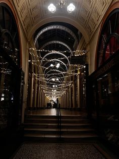 two people are standing in the middle of a hall with lights strung all around them