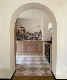 an archway leading into a kitchen with tile flooring and wooden cabinets on either side