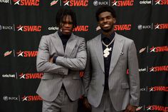 two men standing next to each other in front of a black and red wall with the words swagc on it