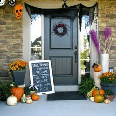 a front porch decorated for halloween with pumpkins and other decorations