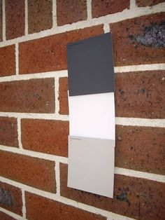 a brick wall with some white and gray paint on the bottom half, and a black and white color block hanging from it's side