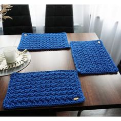 three crocheted placemats sitting on top of a wooden table next to a cup