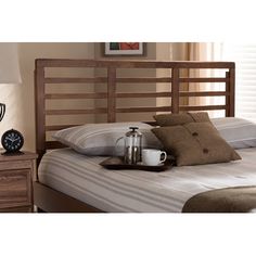 a wooden bed frame with two pillows and a coffee cup on it