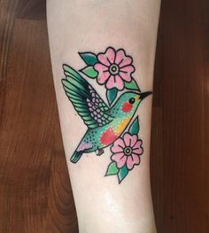 a small bird with flowers on it's leg is shown in this tattoo design