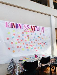 there is a sign on the wall that says kindness wall with sticky notes all over it