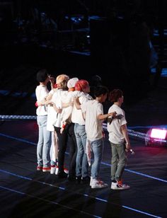 a group of young people standing on top of a stage next to each other with their arms around one another