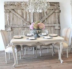 a dining room table with white chairs and a chandelier hanging from the ceiling