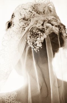 the back of a woman's head wearing a veil with flowers and lace on it