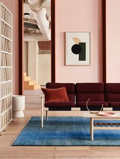 a living room with pink walls and purple couches in the center, along with bookshelves