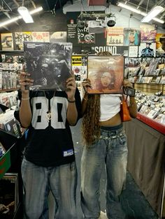 two people are holding up records in front of their faces while standing next to each other