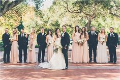 a group of people standing next to each other on a brick floored area with trees in the background