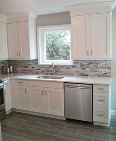 a clean kitchen with white cabinets and stainless steel dishwasher, stove and sink