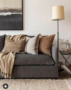 a living room with a couch, lamp and pictures hanging on the wall above it