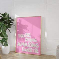 a pink poster with the words you're doing amazing sweet on it next to a potted plant