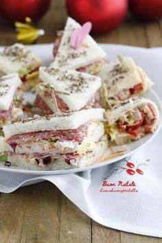 a white plate topped with cut in half sandwiches next to red christmas ornaments on a wooden table