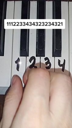 a person is playing the piano with numbers on each side and one hand that is touching the keys