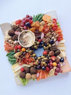 an arrangement of fruits and vegetables arranged in the shape of a wreath with a dip