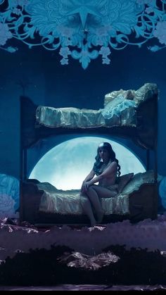 a woman sitting on top of a bed in front of a giant blue moon above her