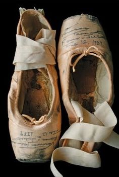 an old pair of ballet shoes with ribbons tied around the soles, in black and white