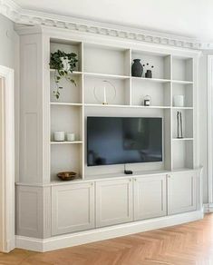 a living room with white bookcases and a flat screen tv on the wall