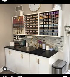 a kitchen with white cabinets and black counter tops next to a large clock on the wall