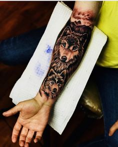 a person with a tattoo on their arm and two wolfs in the middle of it