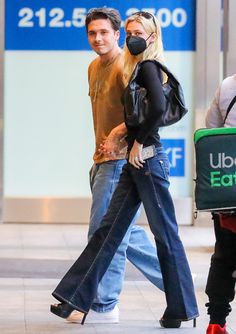 a man and woman walking down the street wearing face masks