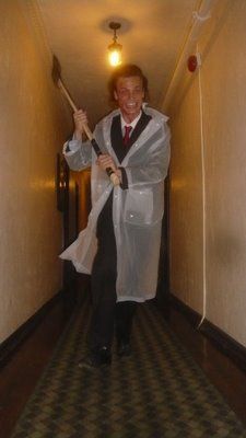 a man in a lab coat is holding a broom and smiling while walking down the hallway