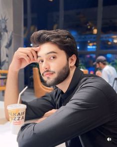 a man sitting at a table with his hand on his head and looking off to the side