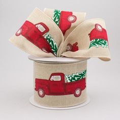 a red truck with christmas trees on it is sitting in a white canister filled with ribbon