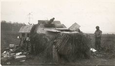 two men standing next to an old tank in the middle of a field with other items