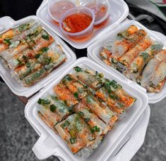 several trays filled with food sitting on top of a table next to cups and sauces