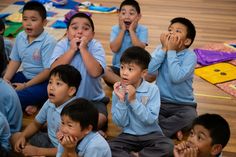 a group of children sitting on the floor with their mouths open and hands in front of them