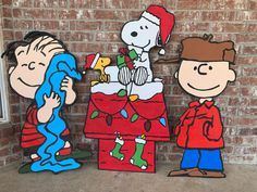 three cardboard cutouts of charlie brown and snoopy on top of a christmas tree