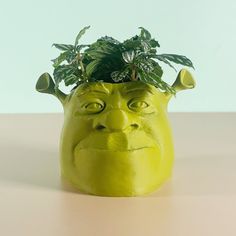 a green planter with an angry face on it's head is sitting on a table