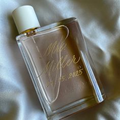 a bottle of perfume sitting on top of a white bed sheet with writing on it