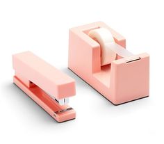 a pink stapler with a roll of toilet paper on the side and a tape dispenser attached to it